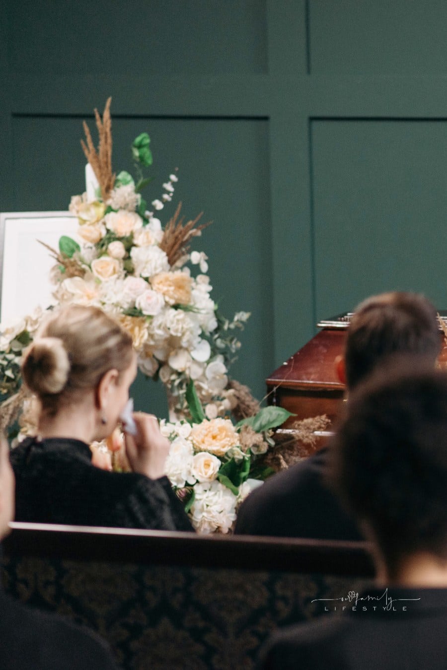 Mourners sitting in pews with a Coffin anf flowers at a Funeral Service