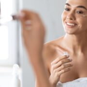 Woman Applying Face Serum Using Dropper Caring For Skin Indoors