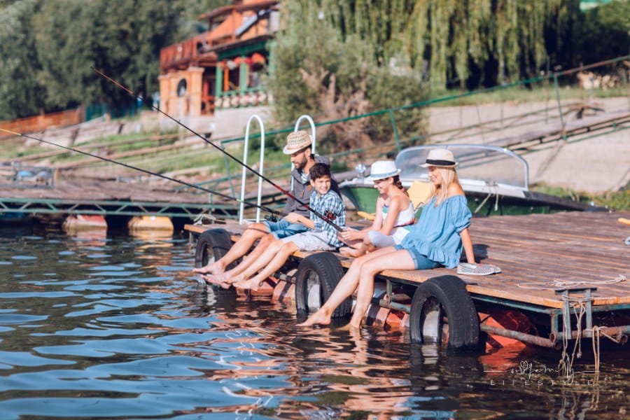 Family spending time together, fishing on jetty by the lake.