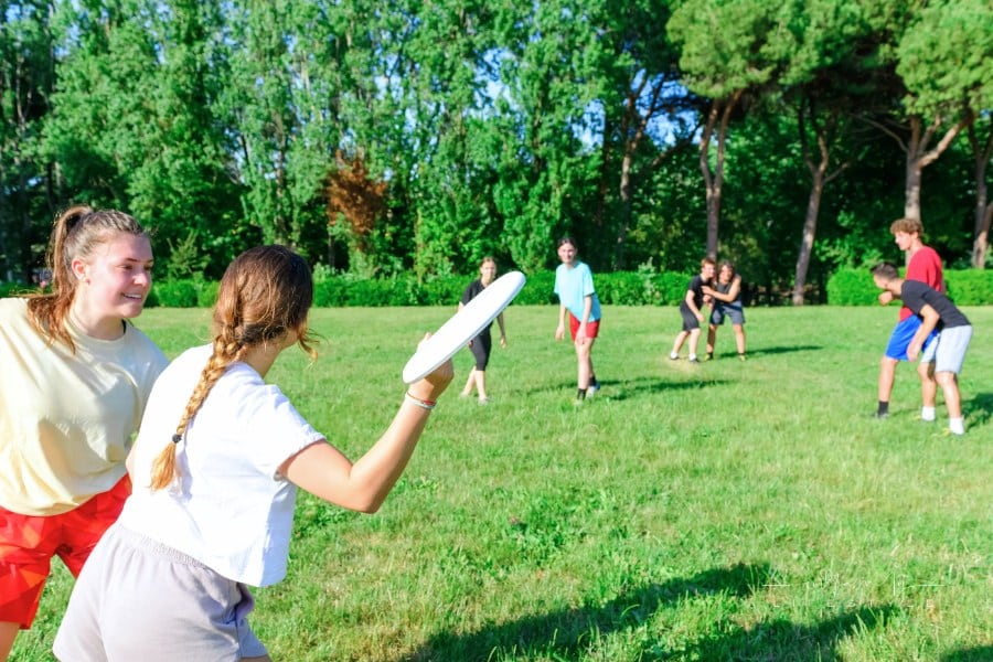 group of teens playing with plastic flying disk in a park