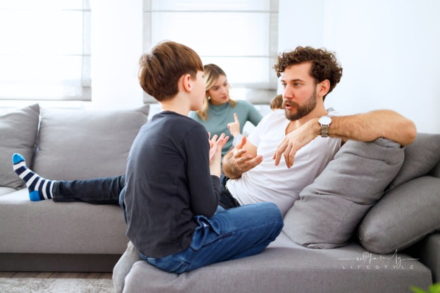 dad talking to son on couch with mom and brother in background