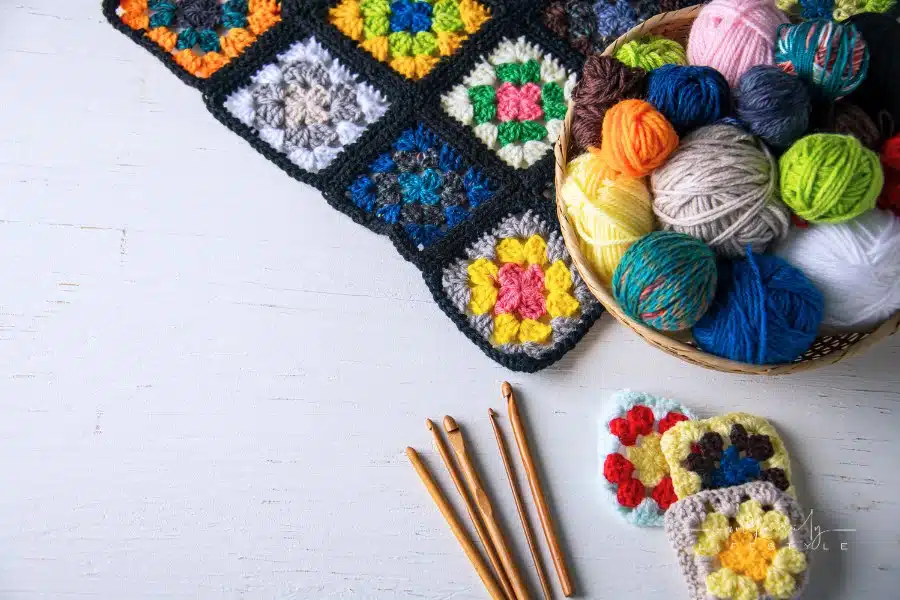 Yarn balls,crochet needles,granny squares on white background.