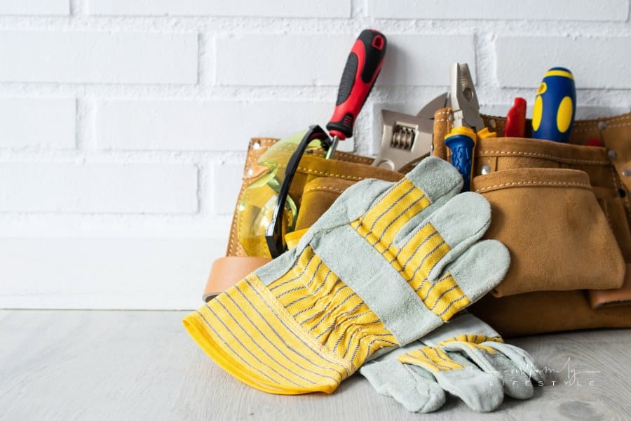 construction tools in a tool belt in front of a white brick wall