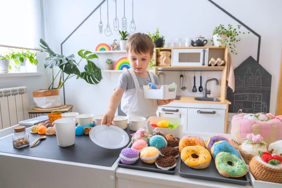 Male baby chef in apron posing at childish kitchen cafe public catering food sweet toys imitation