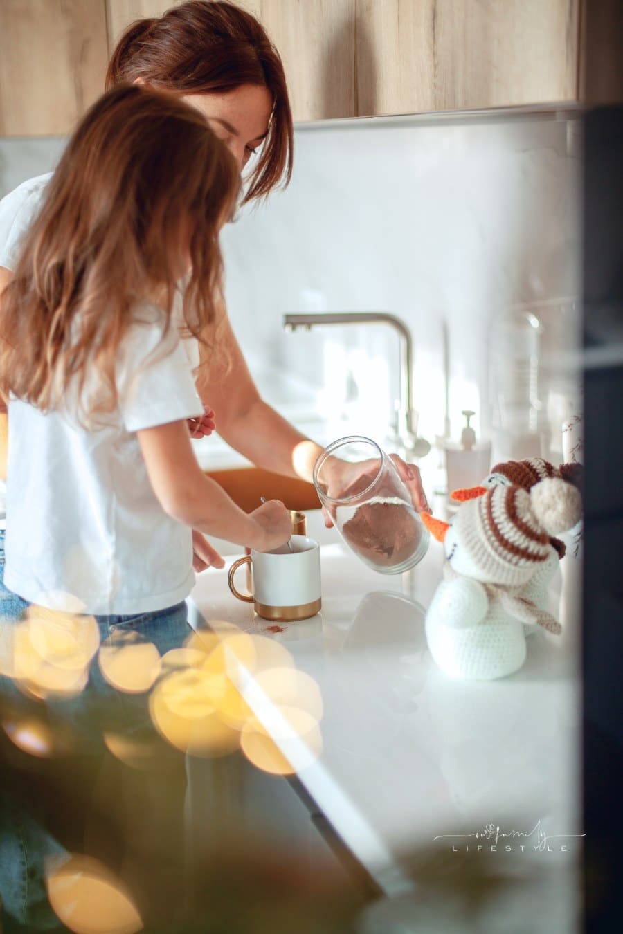 A young beautiful mother and a crying daughter are preparing cocoa in a stylish home kitchen