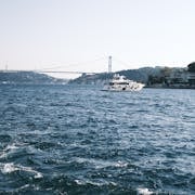 A luxury yacht sailing on the Bosporus with the iconic bridge in the background in Istanbul, Turkey.